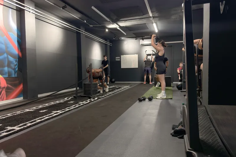 La sala Hyrox di AB Lab: una cliente spinge la slitta sulla corsia, un'altra si allena con un manubrio, altre persone in allenamento sullo sfondo